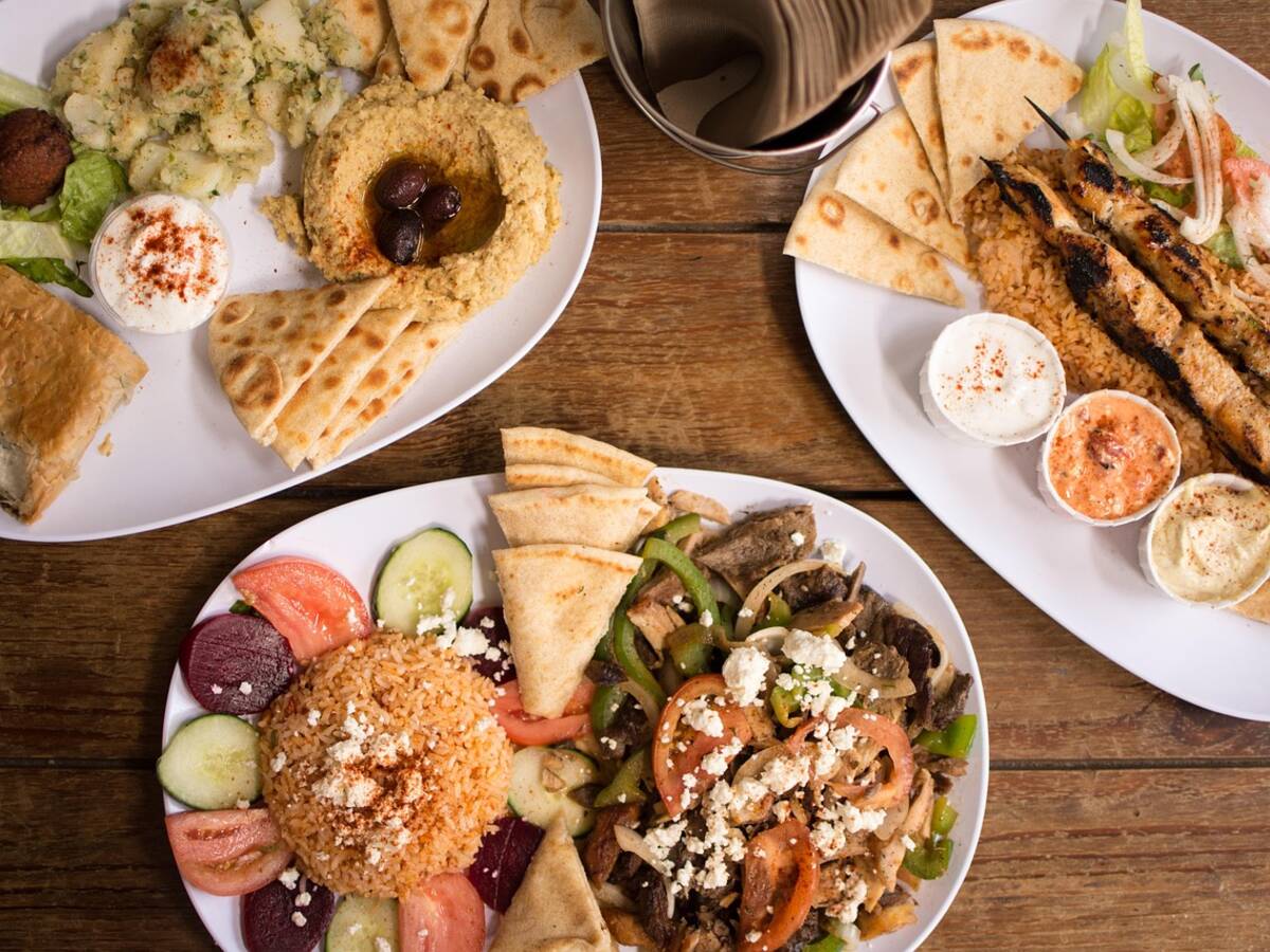 Petites assiettes de houmous, de falafels et de taboulé partagées sur une table